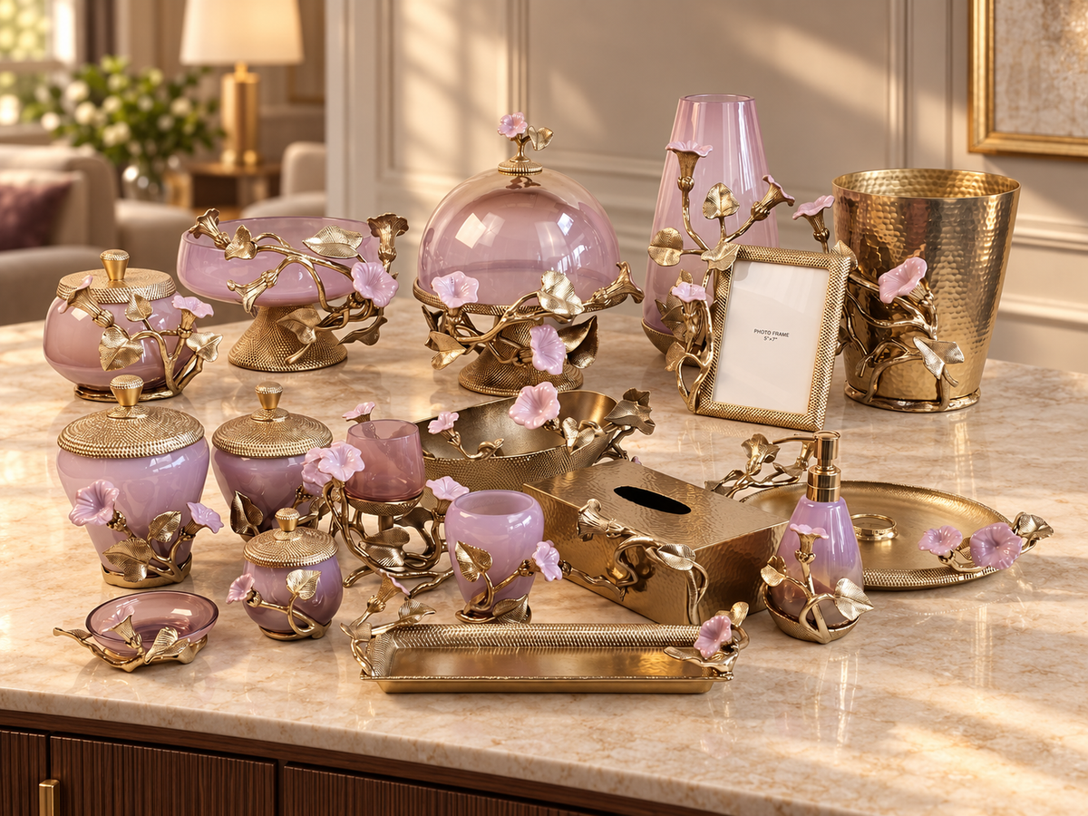 Lavender glass and gold metal home décor collection with floral accents, staged on a marble console in a warmly lit modern living room.