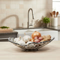 Artistry Deco Sea Coral Onions, garlic, potatoes, and carrots in aluminium bowl on dining table, Singapore stock.